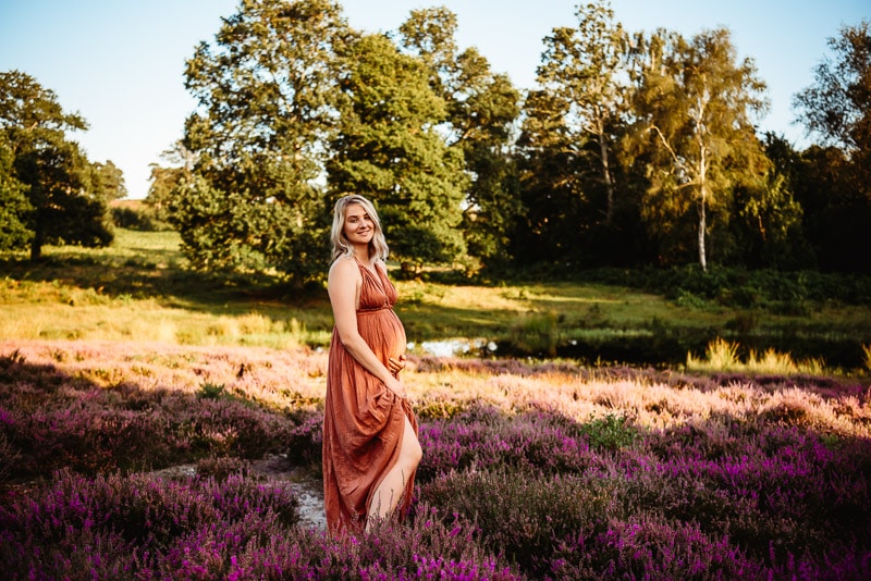 pregnant woman posing in pulborugh surrounded by flowers with vanessa gomes photography