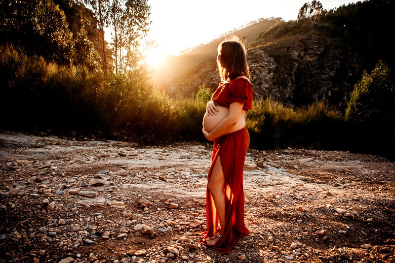 pregnant woman hugging belly looking at the sunset during a maternity photography session with vanessa gomes photography