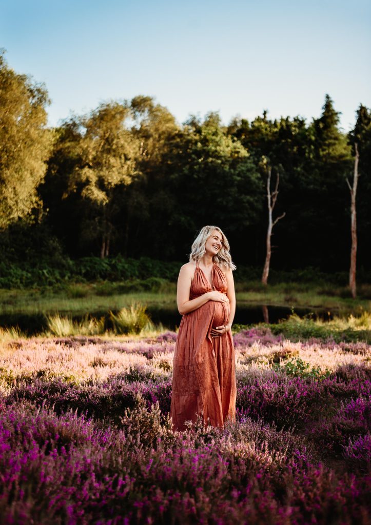 Pregnant women holding belly and smiling during pregnancy photoshoot