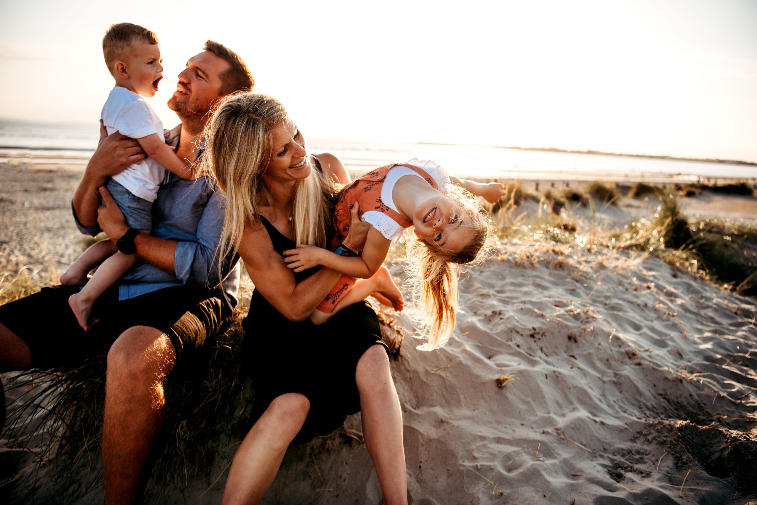 Family sitting on the beach at sunset in West Wittering