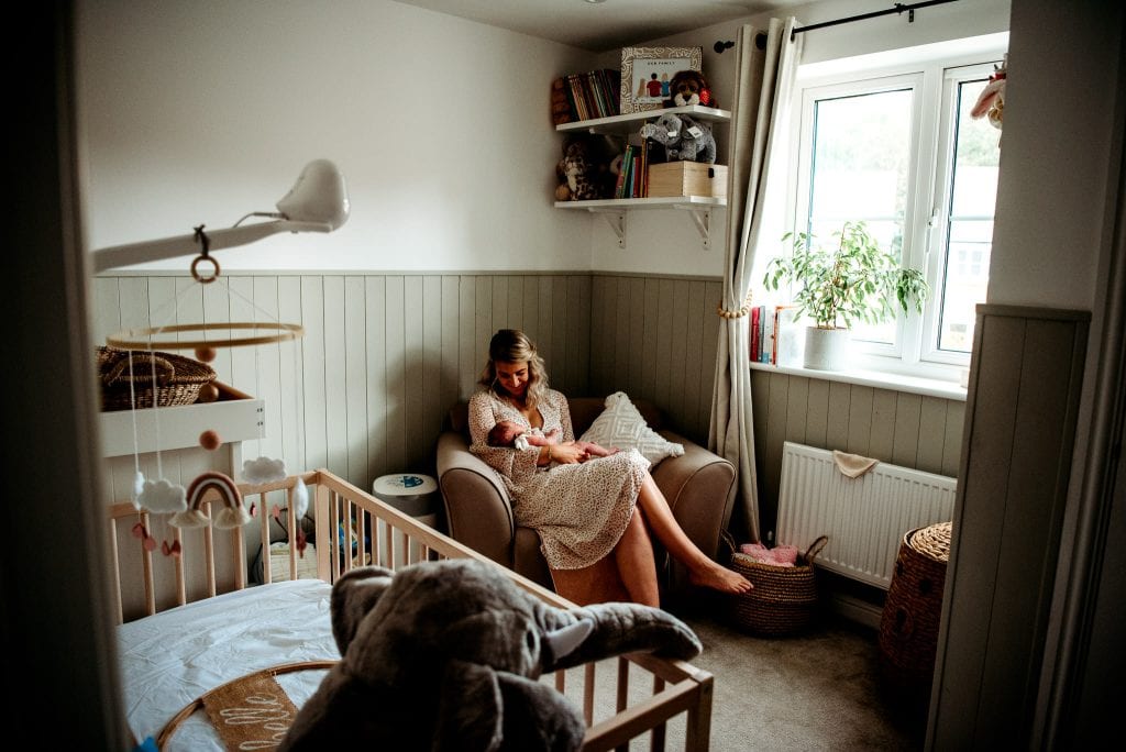 mum nursing newborn in her bedroom with vanessa gomes photography