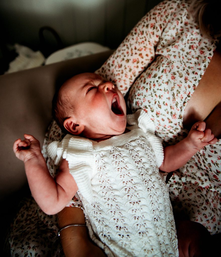 newborn yawning while in mum's arms at in home photography session