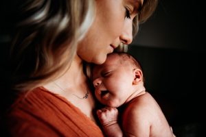mother holding newborn baby with eyes closed with newborn photoshoot at home