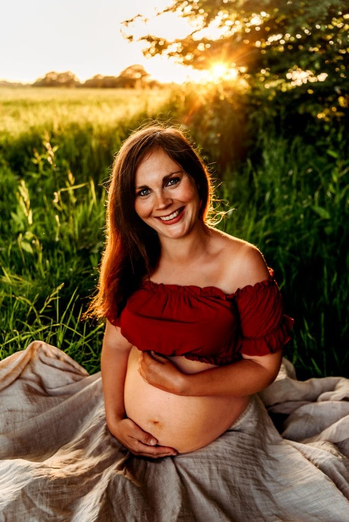Pregnant woman sitting on the floor, holding her belly 