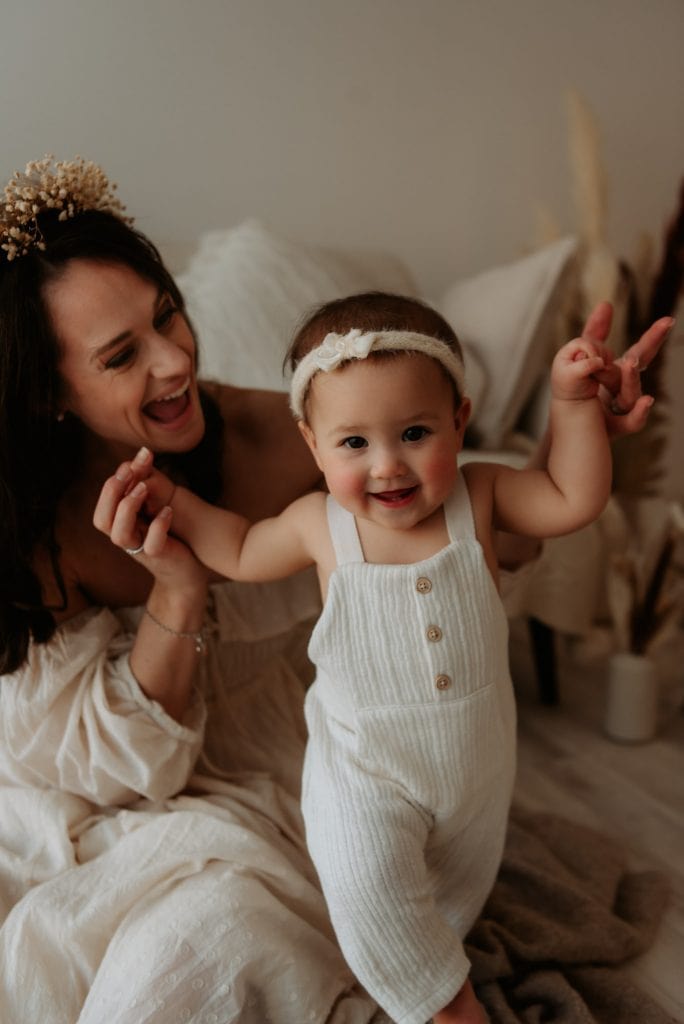 baby smilling while mum is holding her hands