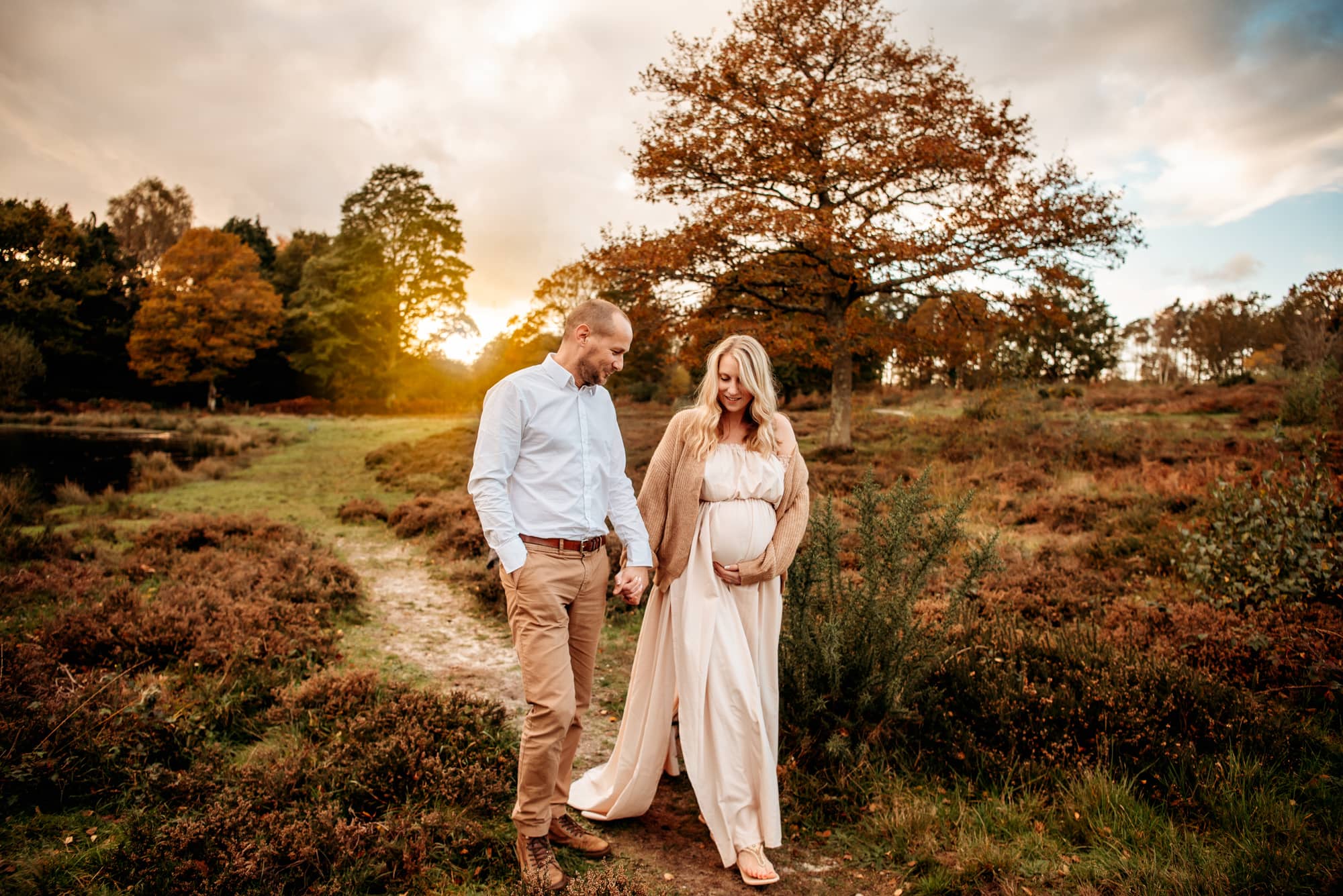 Couple with hands together, she's holding her pregnant belly.