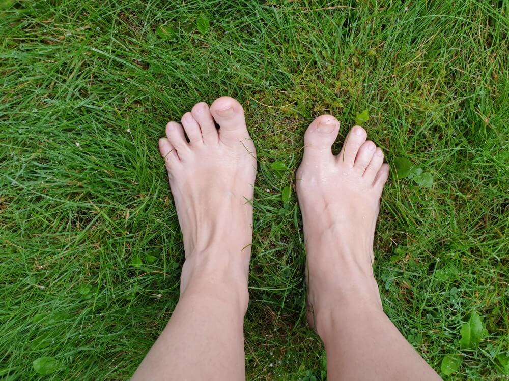 Zwei nackte Füße auf Rasen