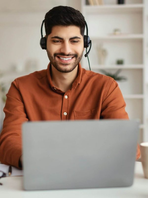 arab-man-using-laptop-wearing-headset-sitting-at-desk.jpg
