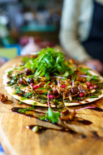 klassieke Flamkuchen veganstyle met gekarameliseerde ui en peer met pomegranate en rucola