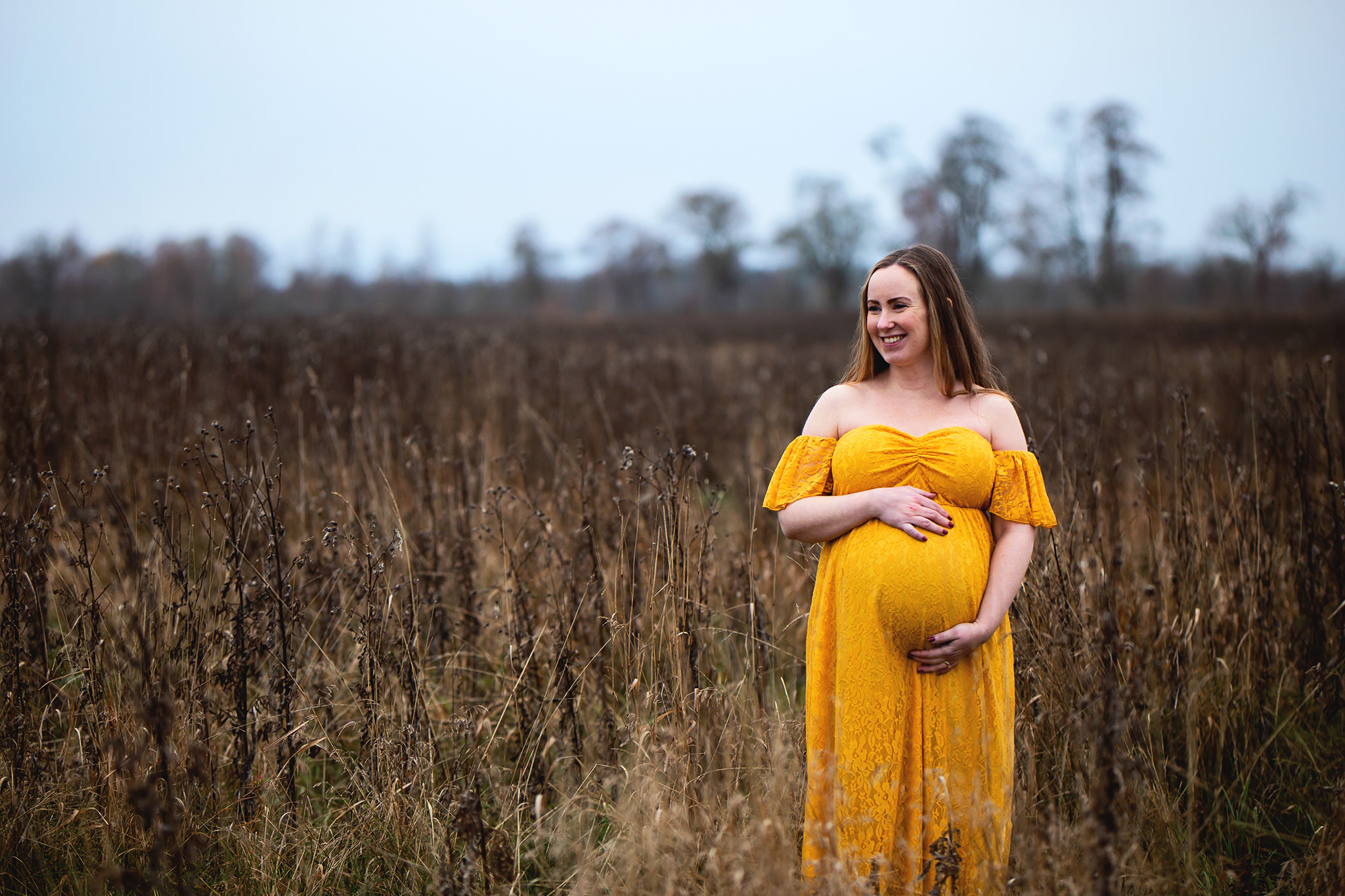 Gravidfotografering på en äng med torrt gräs.