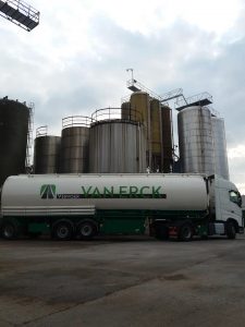 bulkwagen bij laden in fabriek met silo's op achtergrond