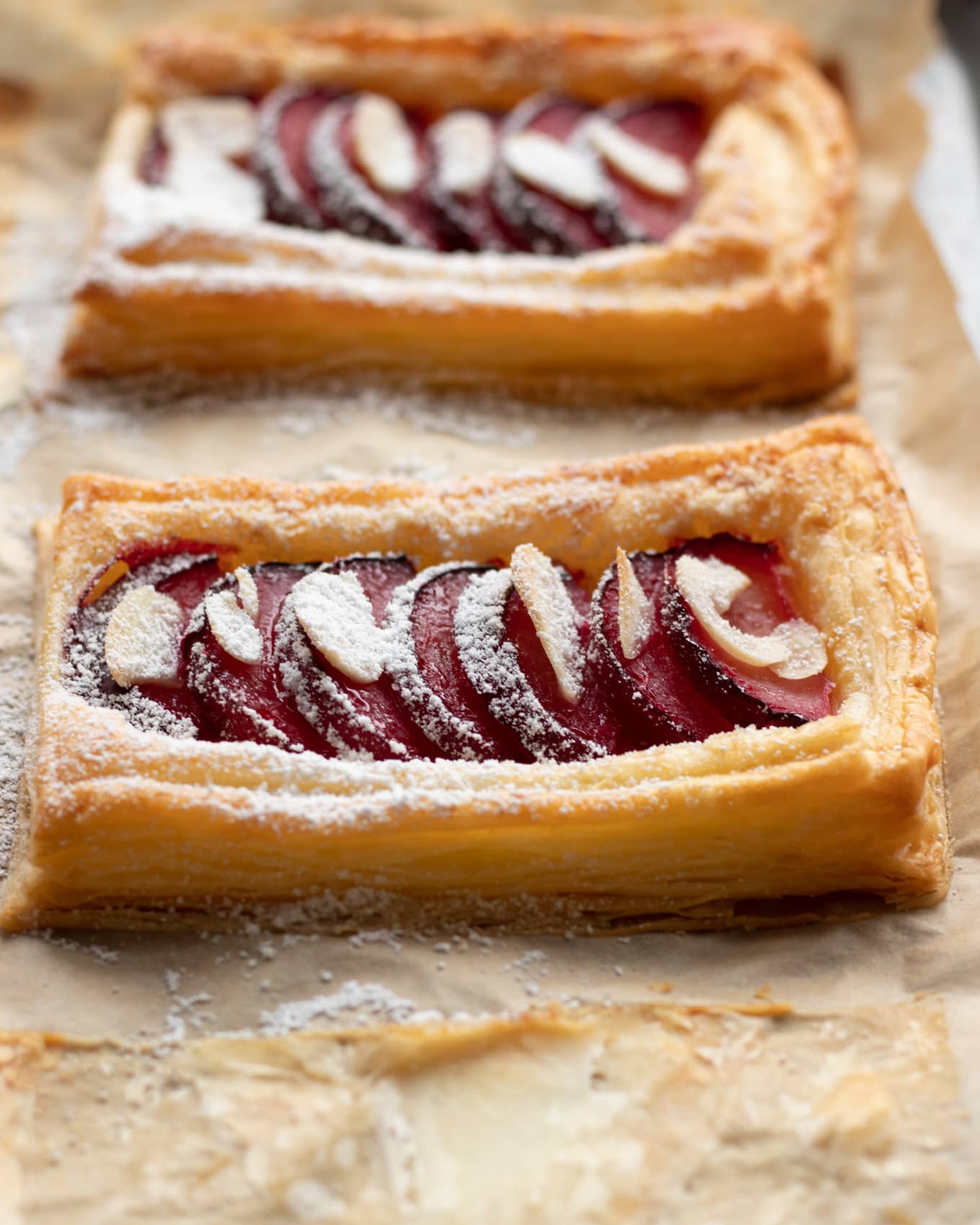 Plum tarts with slices almond and a dust of icing sugar