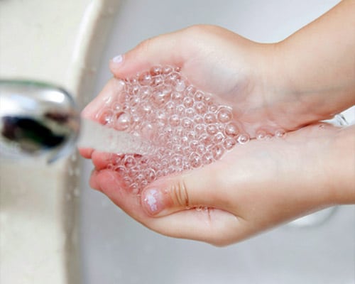 Soft water bubbles into cupped hands - using less soap, saving you money