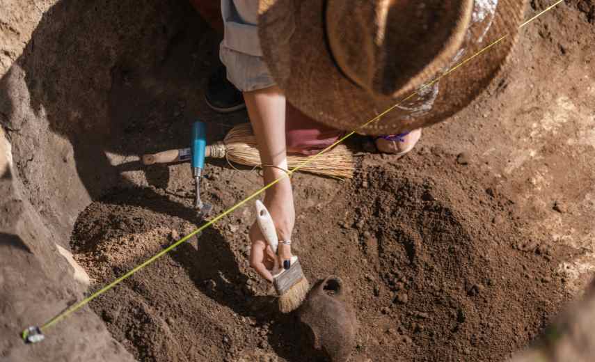 Arkæologi graver forsigtigt i jorden ved brug af pensel