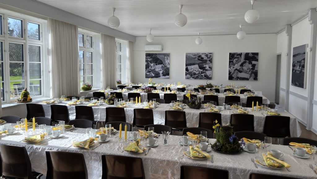 Fire borde dækket med hvide duge, gule lys og dekorationer på.