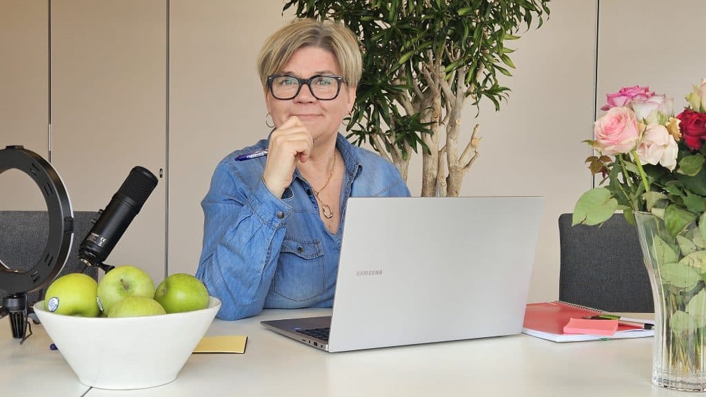 En bild på Pia Nyberg som sitter vid sin dator och tittar in i kameran.