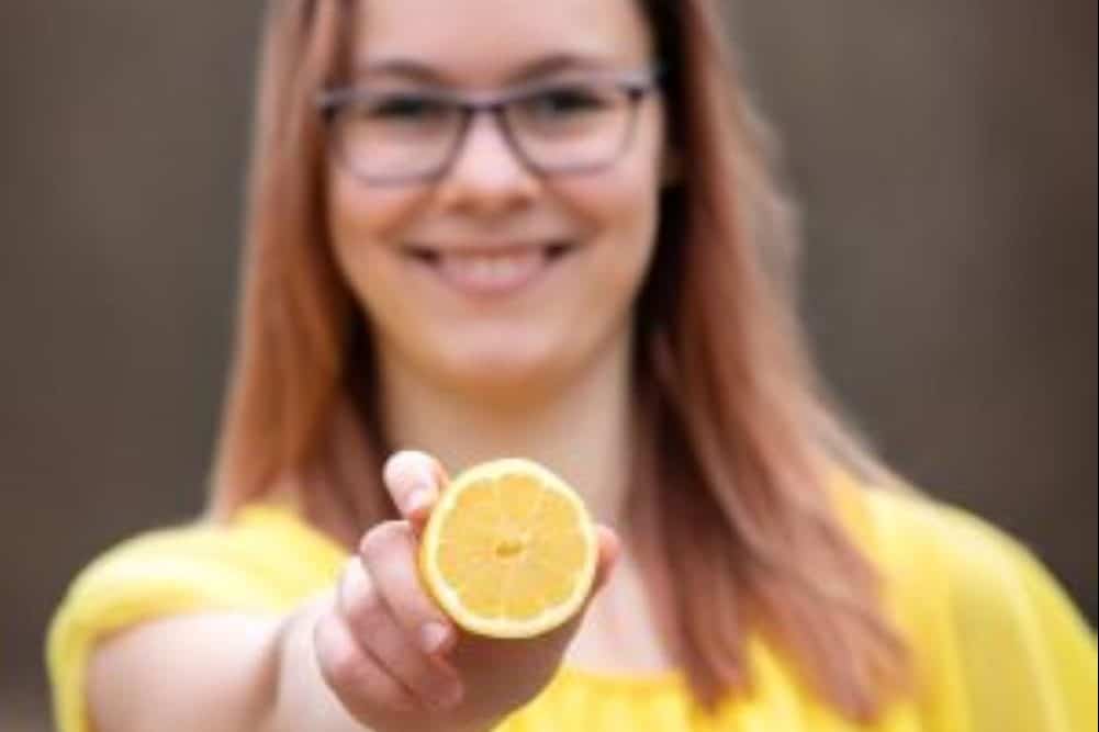 Ich halte lachend eine Zitrone vor mich, ich bin unscharf im Hintergrund zu sehen