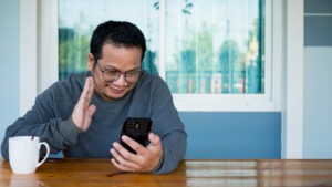 Man wearing long sleeves and eyeglasses sitting and doing video call.