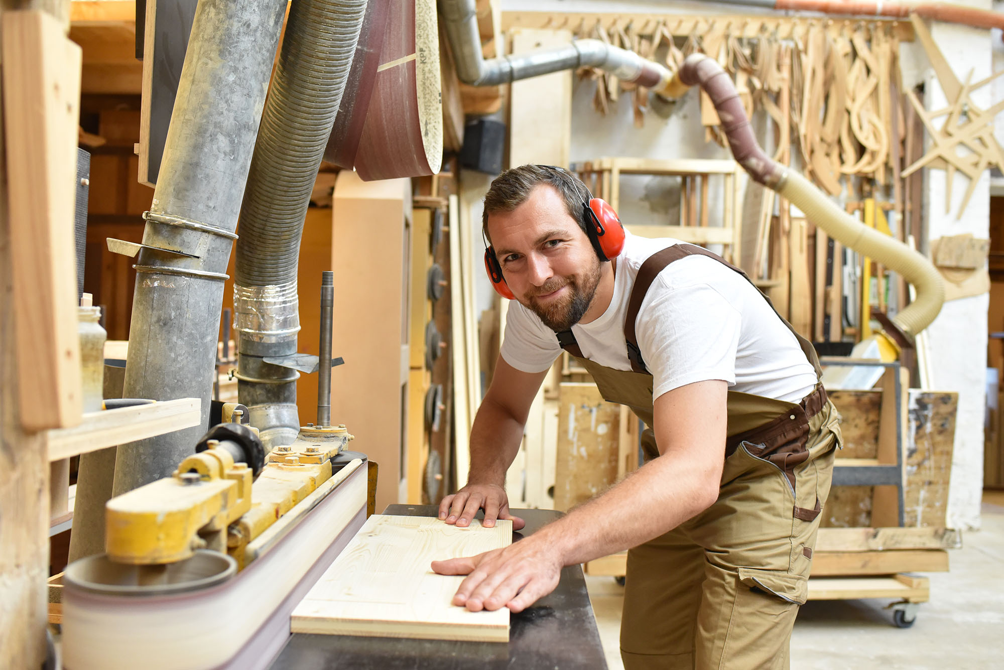 Tischler mit Gehörschutz und Arbeitslatzhose