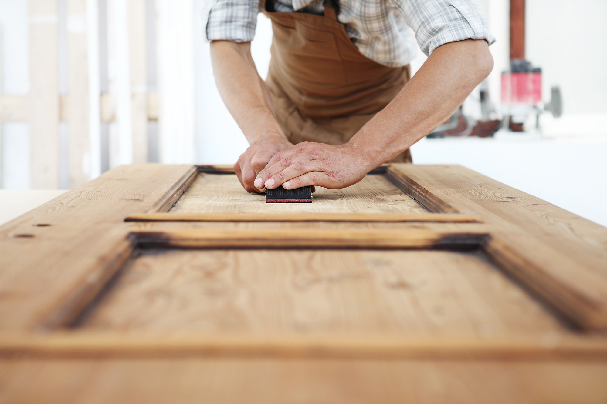 Handwerker schleift eine Tür ab