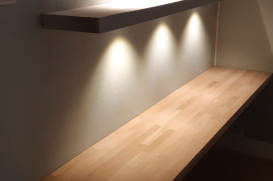 Eiken bureau met zwevende wandplanken met LED spots.