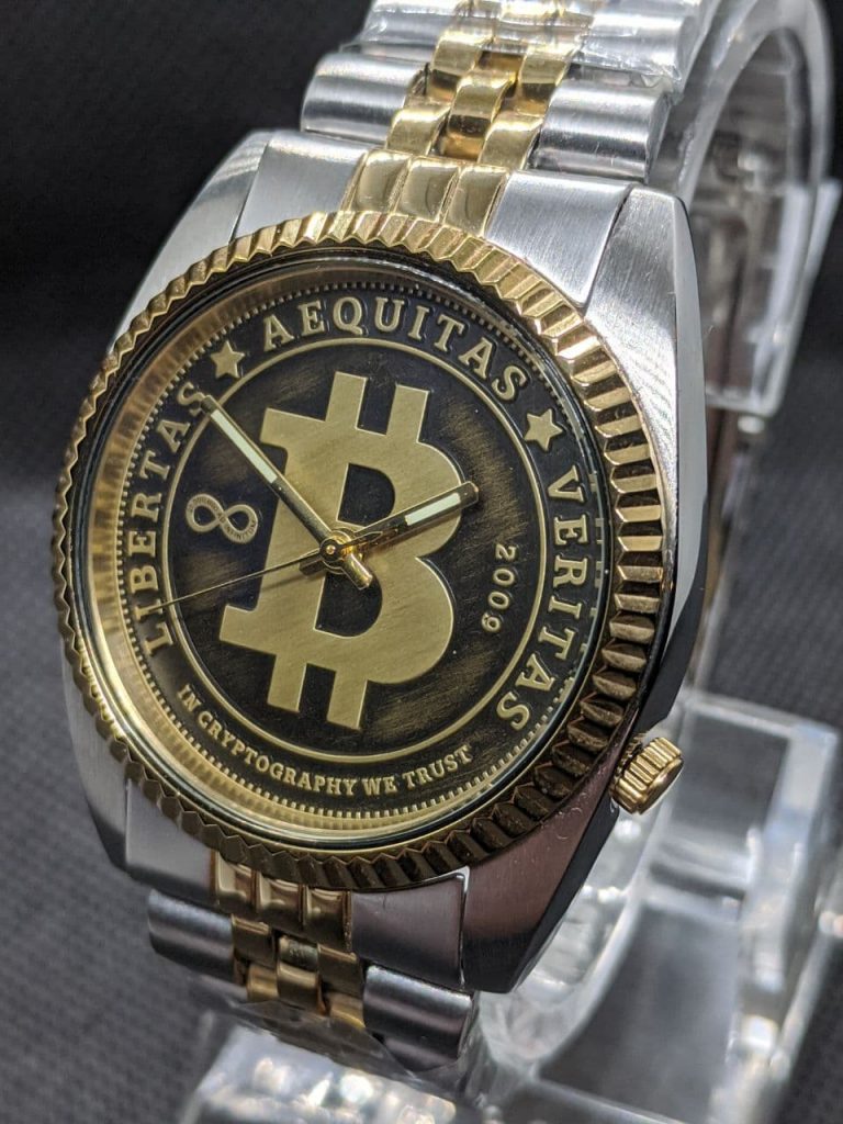Bitcoin Watch - DateJust Styled Bitcoin Dial with Seiko NH36 Movement. Stainless Steel case and gold plated crown & fluted bezel. The watch is finished with a bi-metal coloured jubilee bracelet. The dial is styled like circulated coin the raised areas are gold coloured with a brushed finish and the lower pressed arease are black with a light brushing of gold colour. The dial reads, Libertas,  Aequitas, Veritas, In cryptography we trust dated 2009 when bitcoin was born 