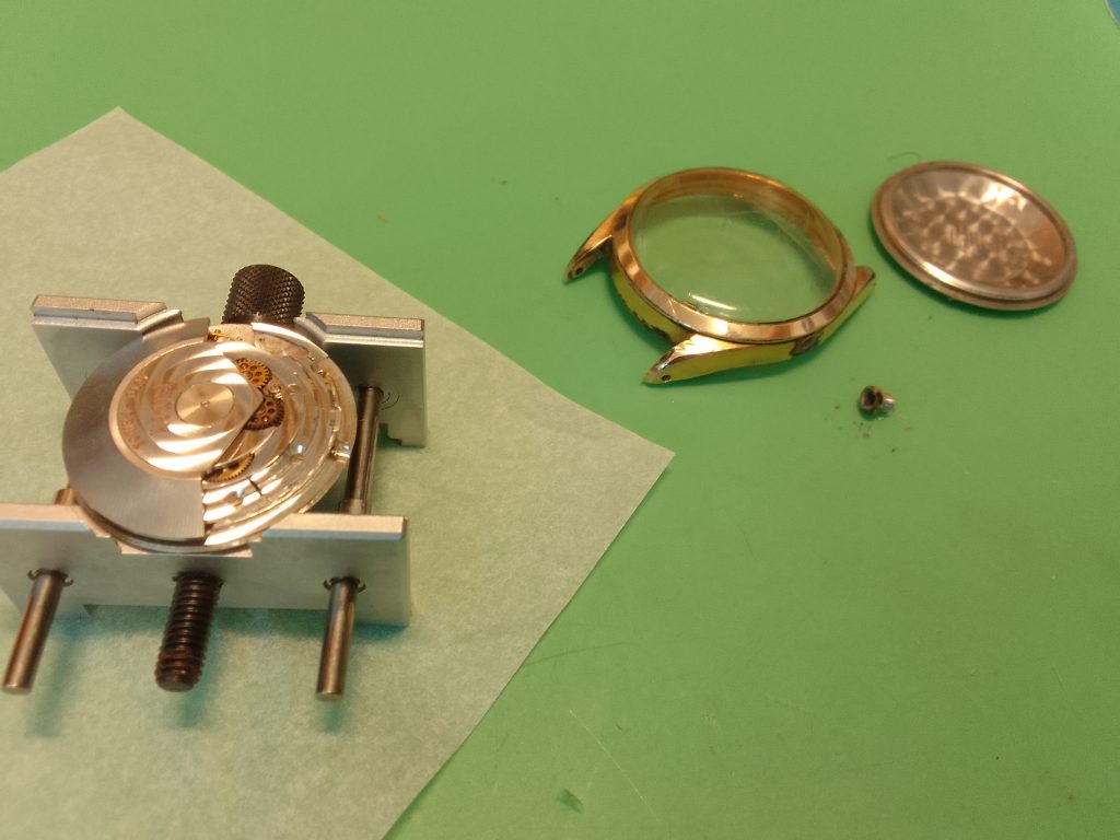 Watch Crown Repair Service: Restore Your Timepiece's Functionality- Tudor 7565 Gold plated case photo displays the extremely corroded tube removed from the case.The case case back and movement are also in the photograph. 