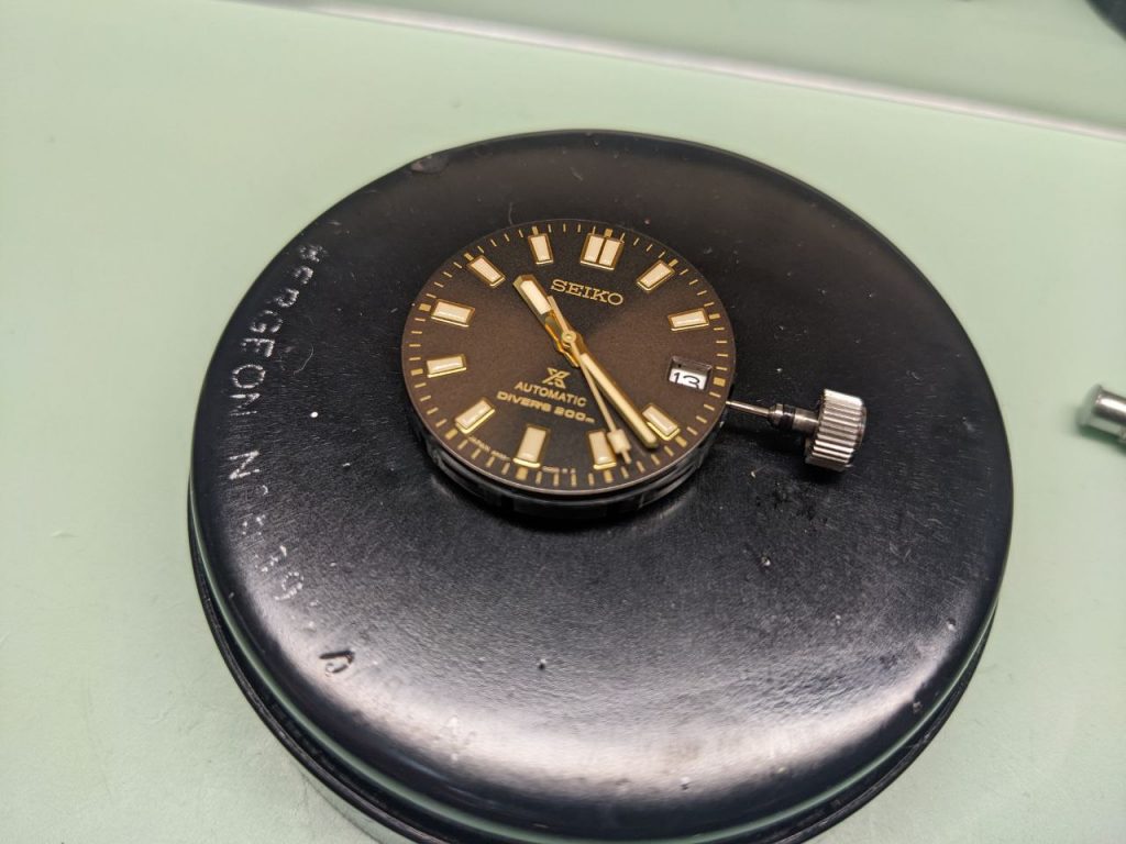 Seiko 6R35 Repair - hands dial and movement removed from case displayed on a watchmakers cushion