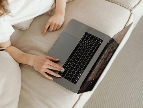 pexels-photo-7603056-7603056 Close-up of a person working from home on a laptop, comfortable on a beige couch.