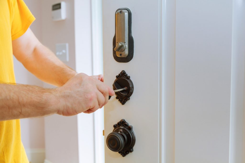 Closeup of a professional locksmith installing or repairing a new deadbolt lock on a house door with
