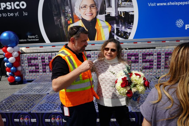 Julien Verdure, a maintenance/engineering associate manager, left, congratulates Nora Chagolla, the first woman in manufacturing at PepsiCo's Riverside facility, during a Friday, March 22, 2024, ceremony to unveil a truck with her photo on the side. Chagolla's career spans more than three decades. (Courtesy of Craig Collins, PepsiCo)