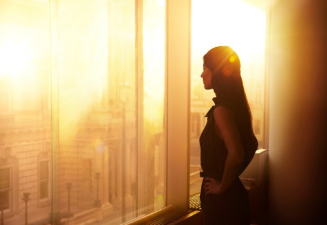 Business woman looking over the city at sunrise.