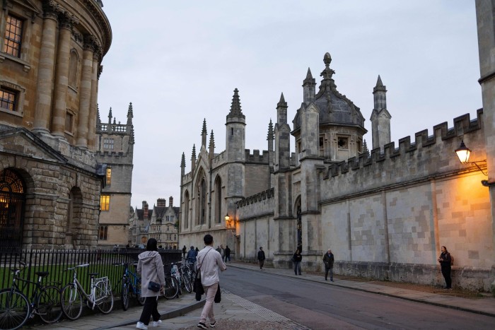 People walk outside the College of All Souls, in Oxford