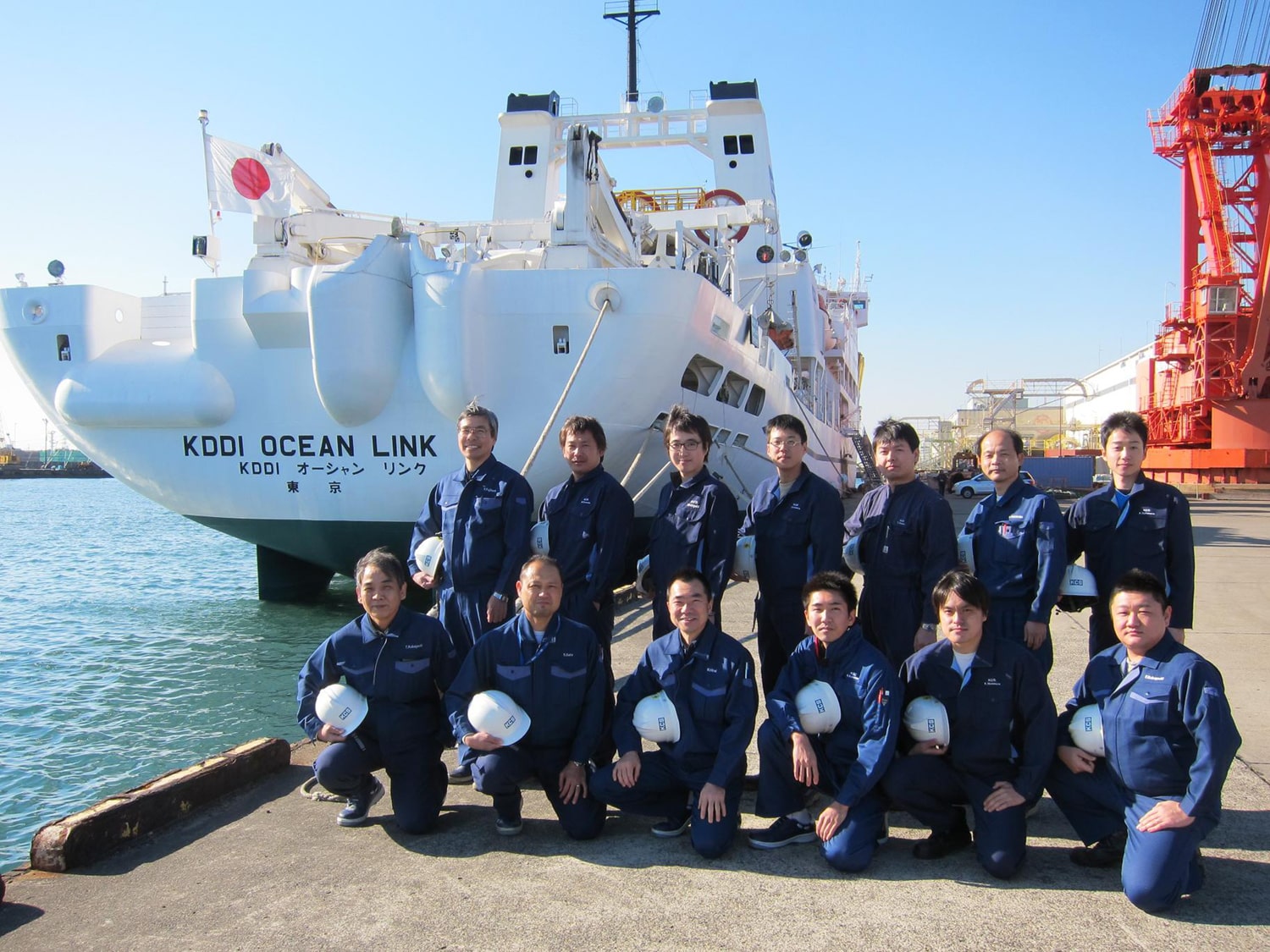 A group photo of the crew of the Ocean Link in 2011. The ship itself is in the background.