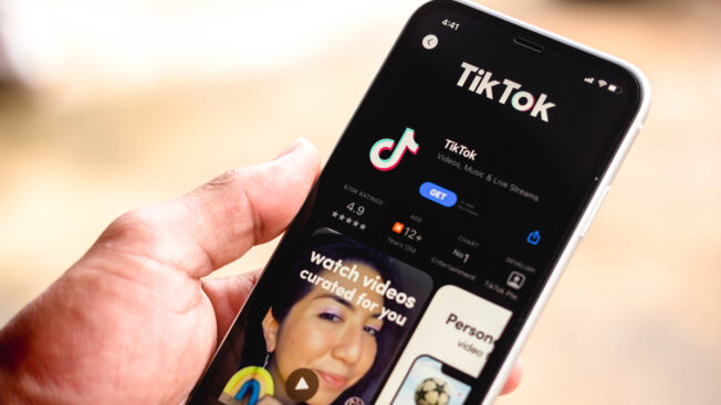 a person's hand holding a cellphone showing the tiktok app