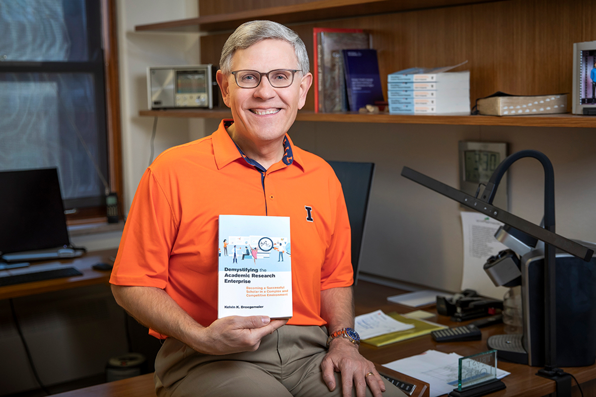 Portrait of Kelvin Droegemeier hold a copy of his new book