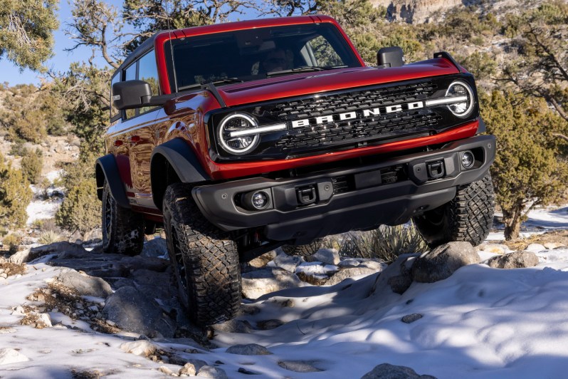 2022 Bronco Wildtrak with optional HOSS crawling over snow and rocks in the wilderness.