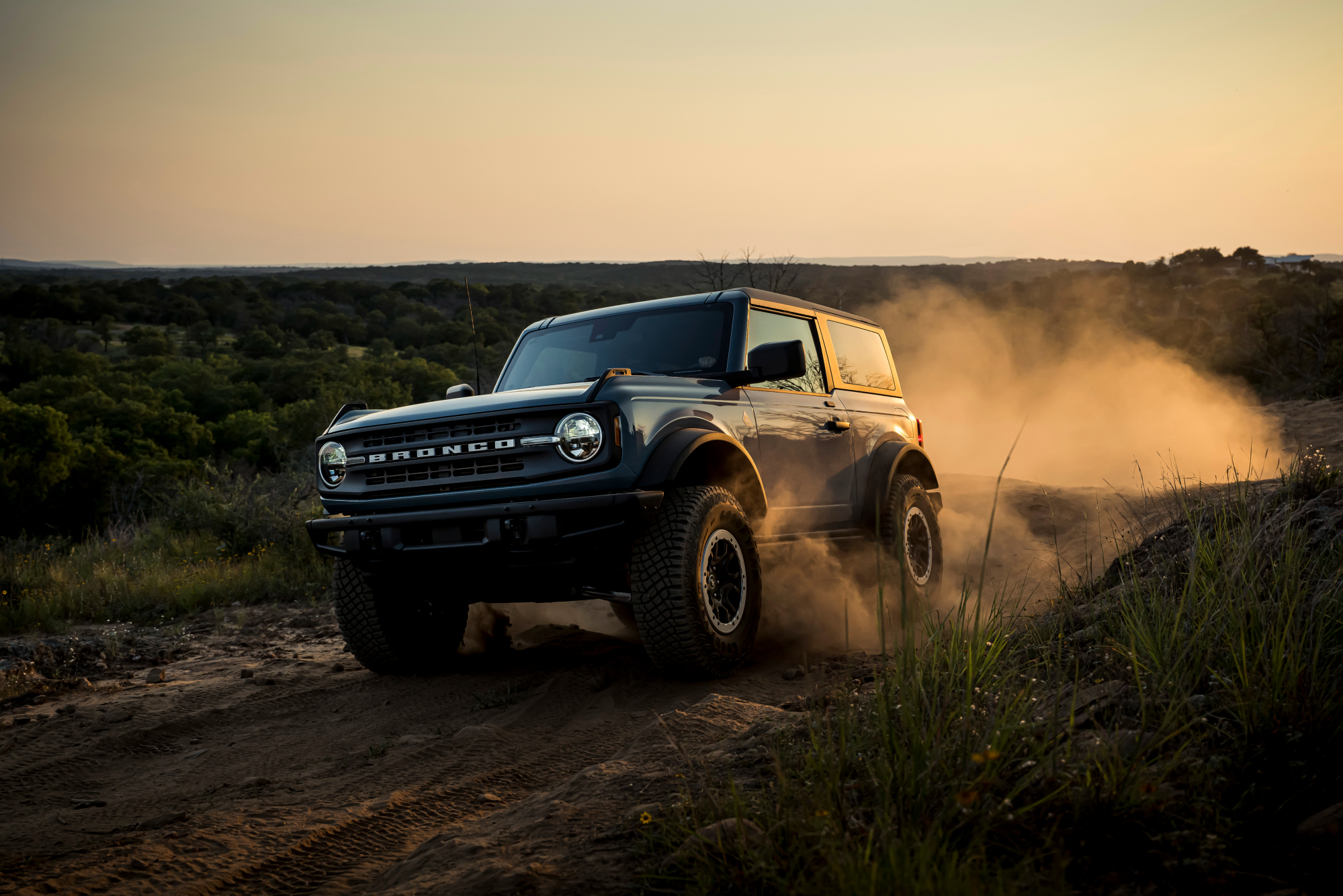2021 Ford Bronco 2-door speeding on a dirt road in the desert.