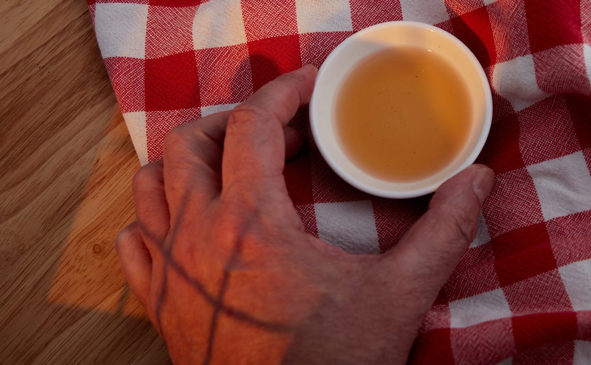 Hand holding a small cup of apple cider vinegar