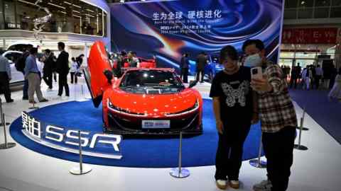 Visitors take selfies in front of a Hypar SSR car on display