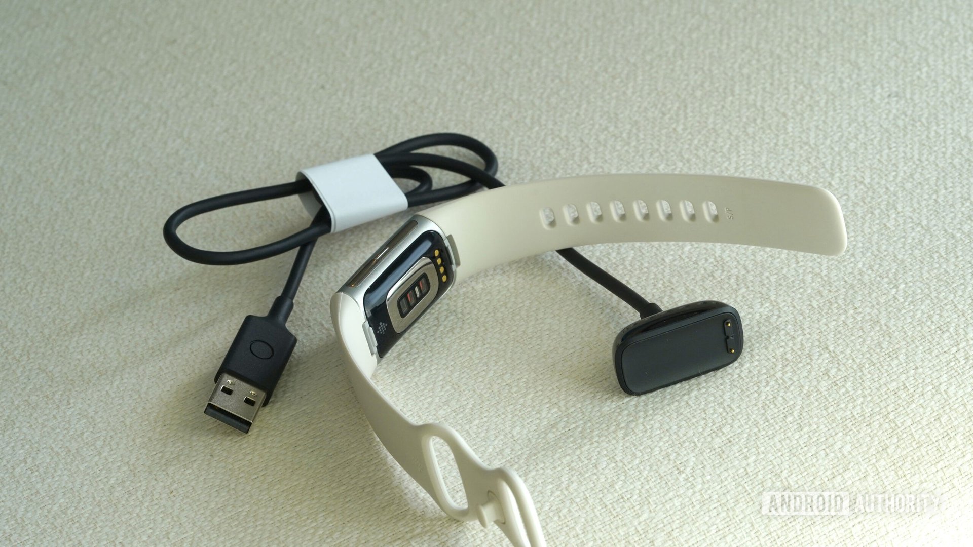 A Fitbit Charge 6 rests alongside its charger.