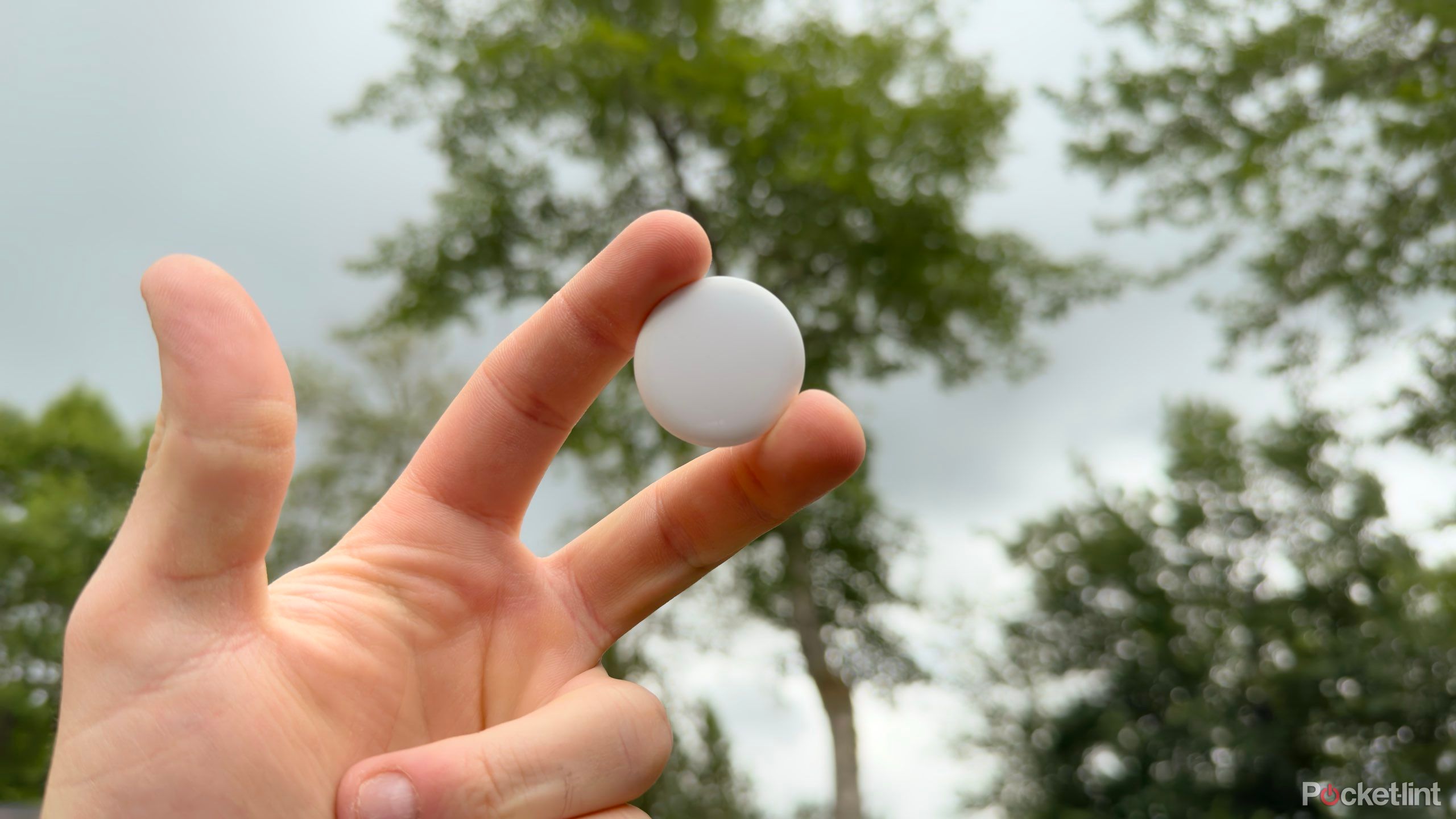 An Apple AirTag in a man's hand.