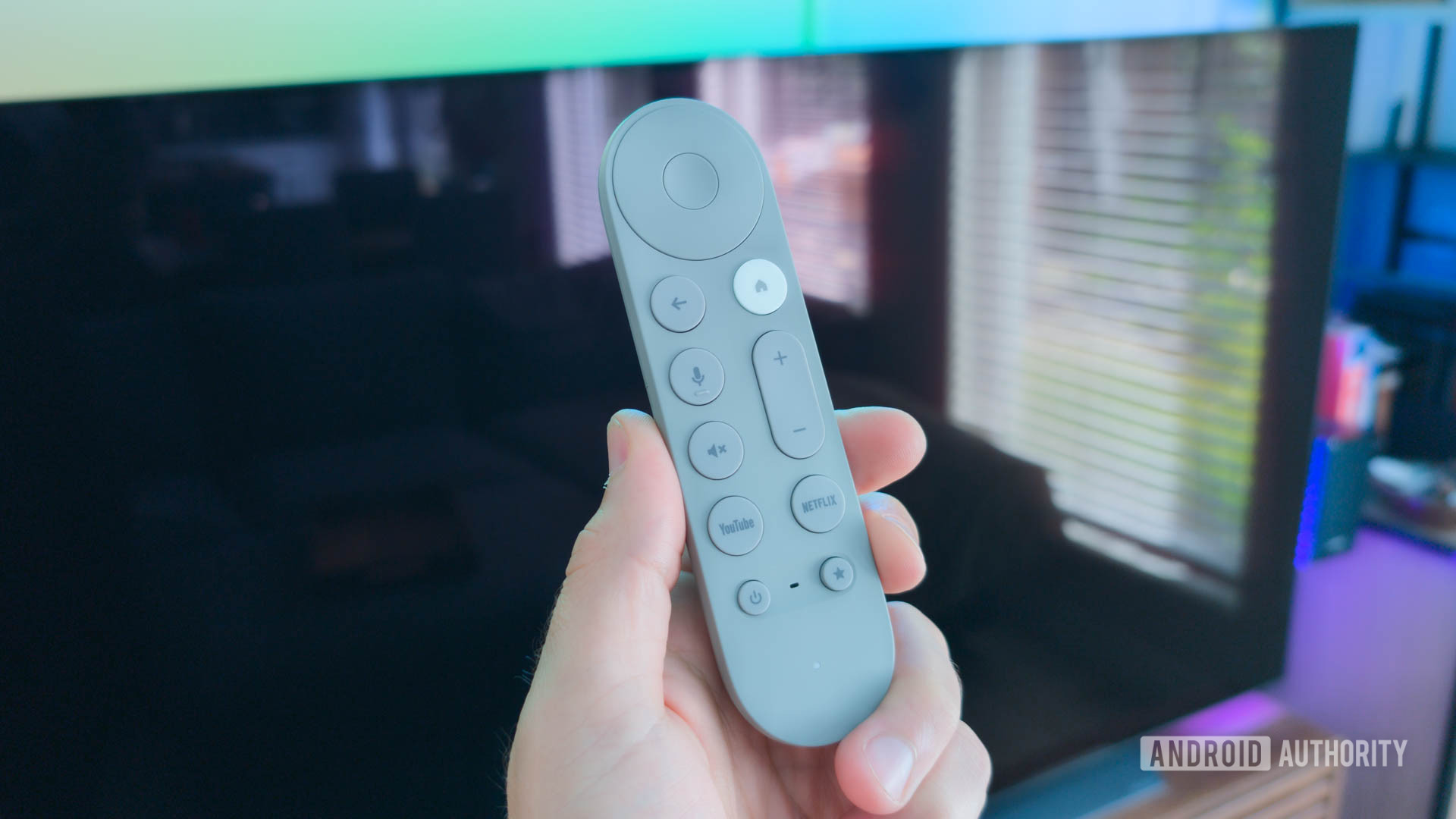 Google TV Streamer remote in hand in front of blank TV