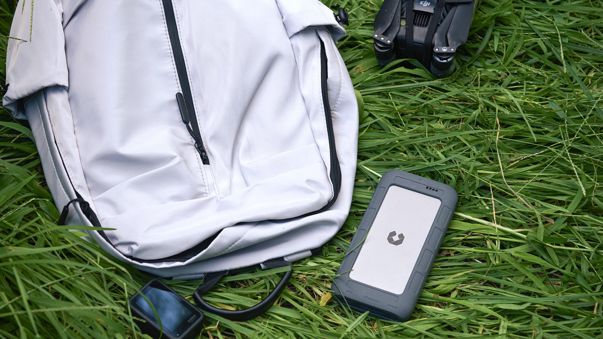 UnifyDrive UT2 on the grass next to a backpack, drone, and camera