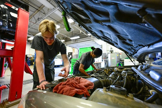 From left: Silver Creek junior Chase Olson and Longmont senior Michelle Zavala work on a car for a woman in need at the St. Vrain Valley School District Career Elevation and Technology Center in Longmont on Thursday. (Matthew Jonas/Staff Photographer)