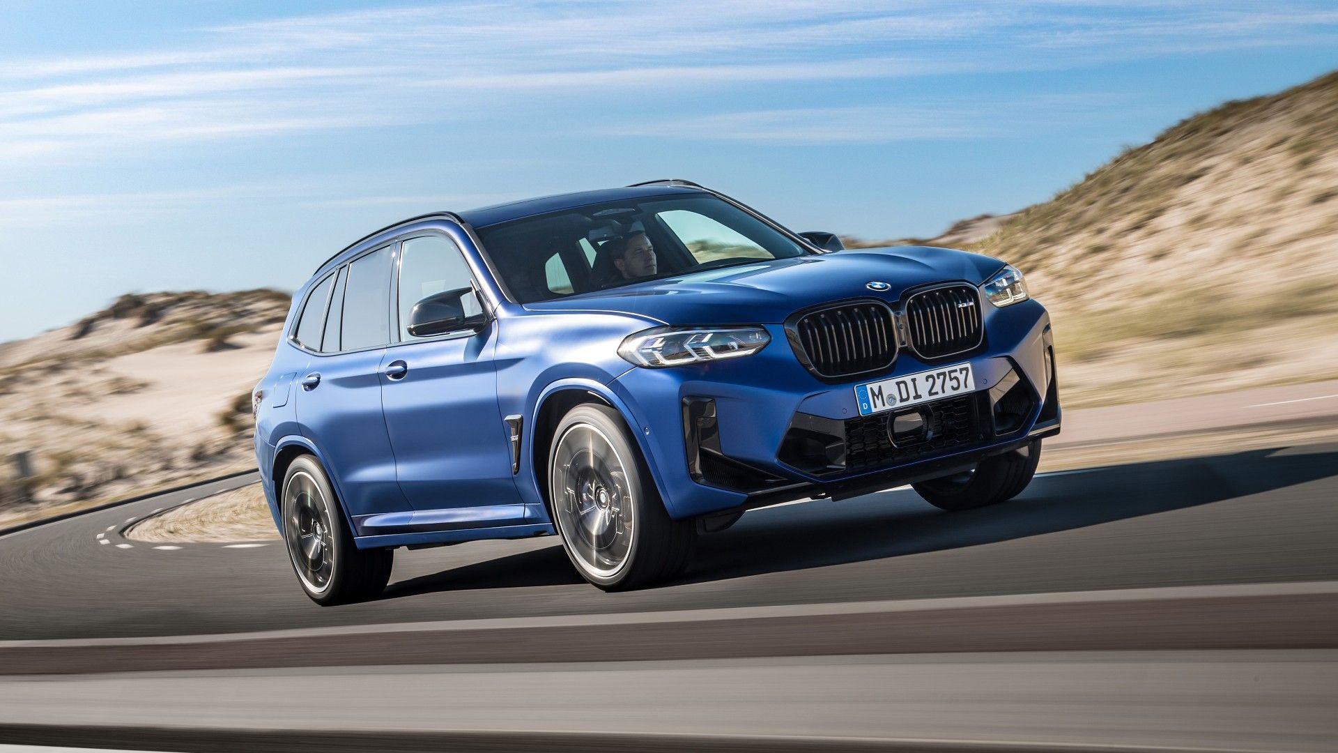 Blue 2024 BMW X3 M Competition driving on a highway