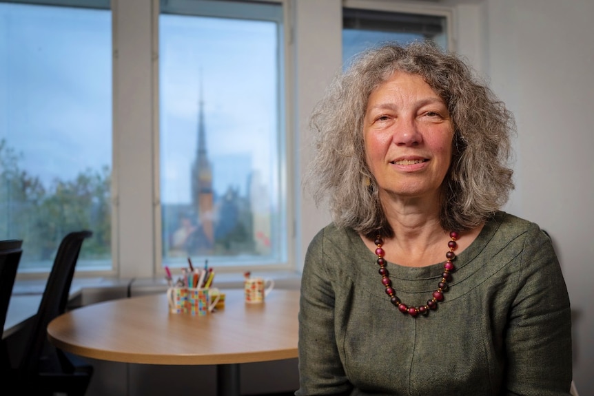 A woman sitting in an offie and smiling at the camera.