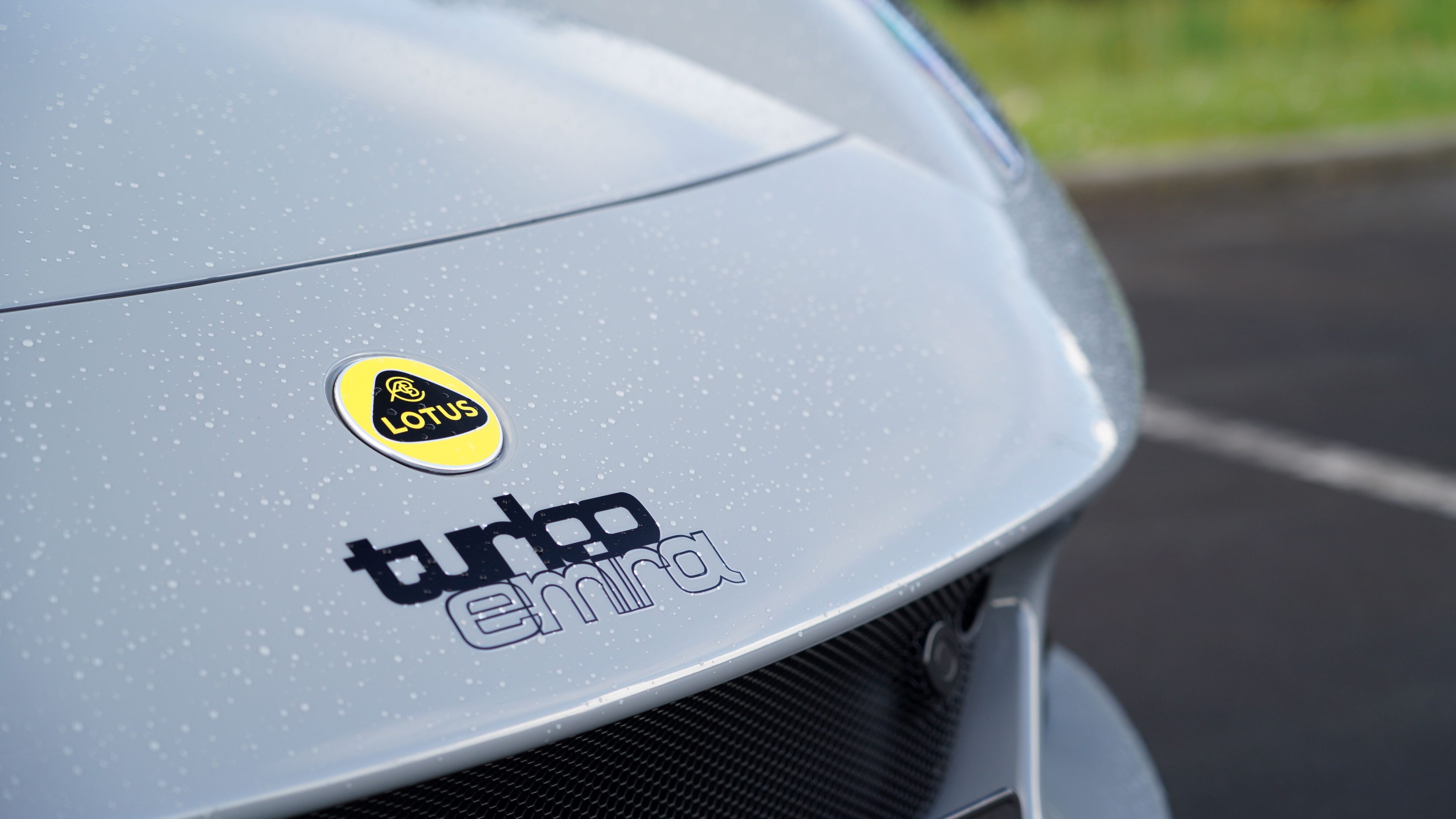 'Turbo Emira' stickers on the nose of a 2024 Lotus Emira i4 Turbo in Nimbus Grey.