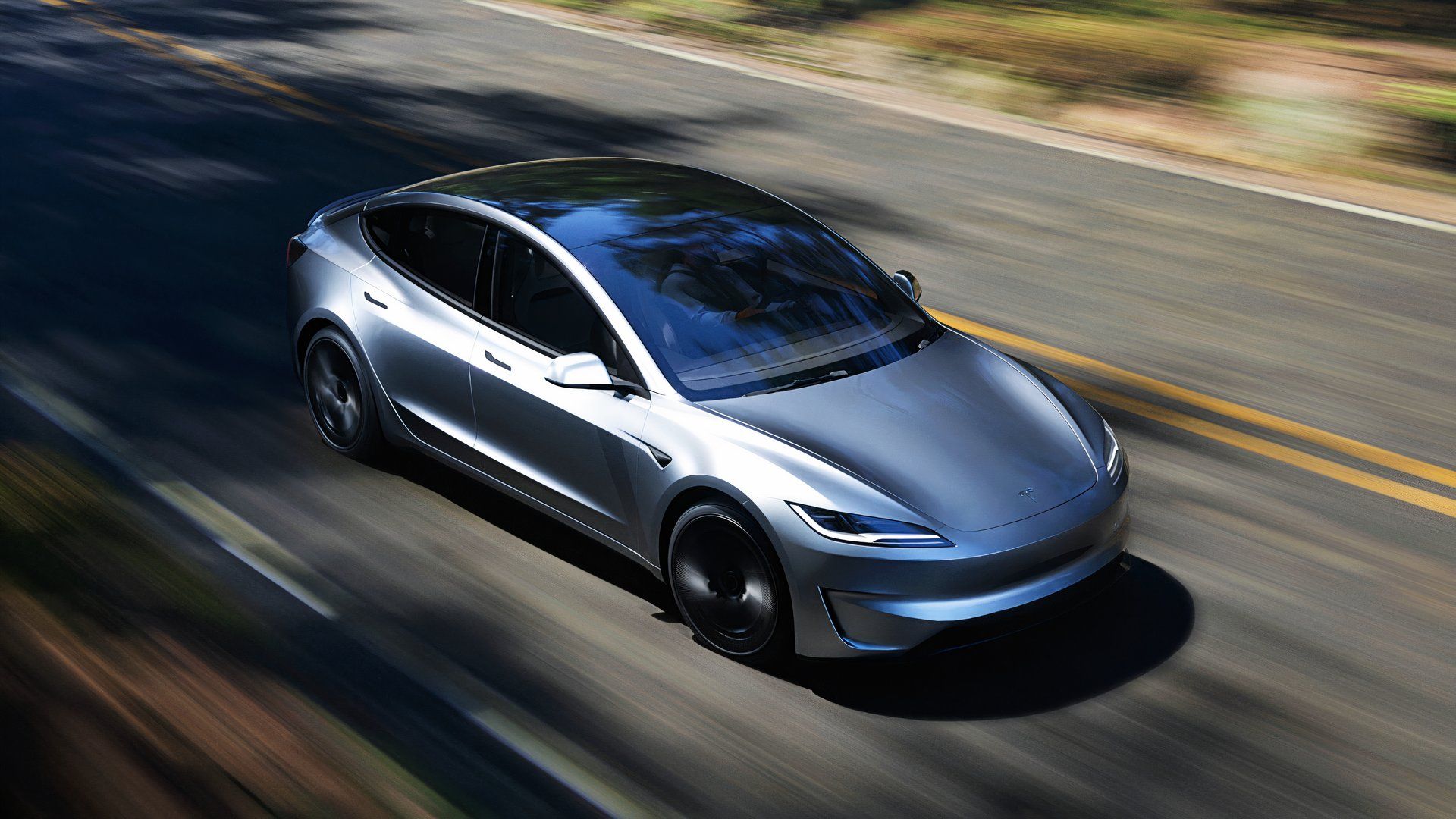 A gray Tesla Model 3 Performance electric car is driving on the road. 