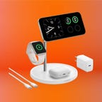 White wireless charging station charging an iPhone, Airpods and an Apple Watch, displayed against an orange background